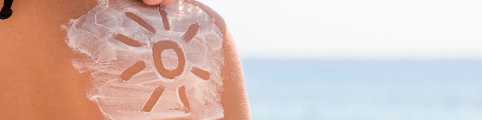 spalla della donna con il sole disegnato con la crema