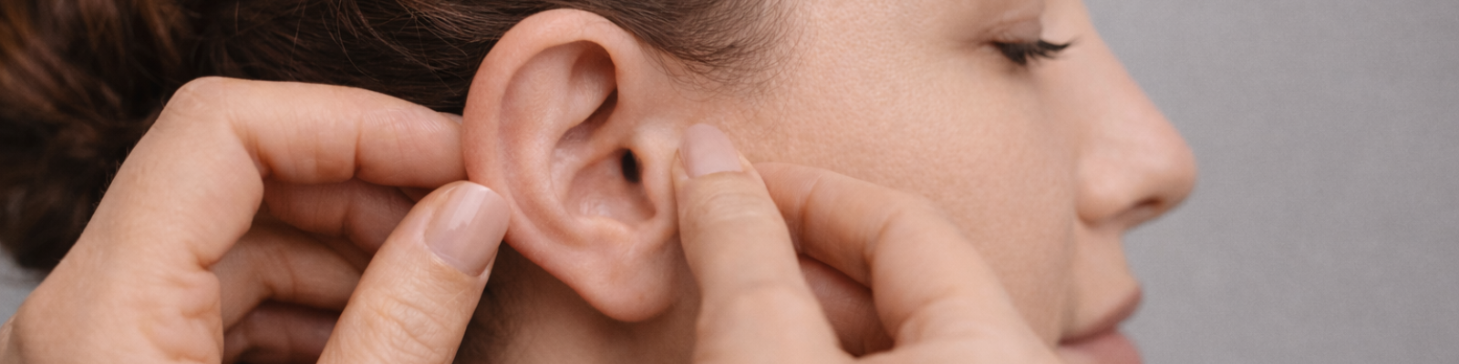 orecchio di una donna toccato dalle mani del medico